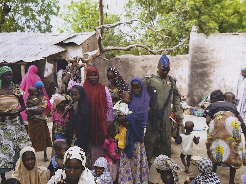 Een Nigeriaanse soldaat bij een groep vrouwen en meisjes die gered werden uit de handen van Boko Haram.