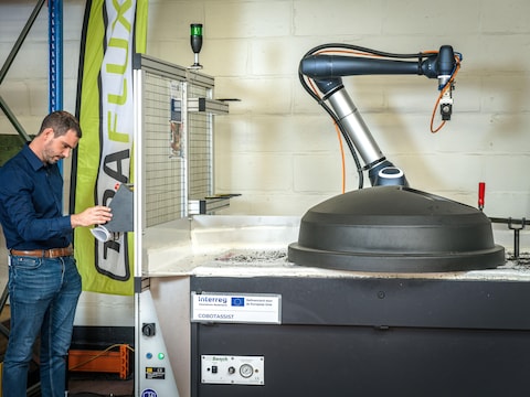 De robot staat tussen de andere machines op de werkvloer en wordt ingezet binnen de normale werking van de fabriek.