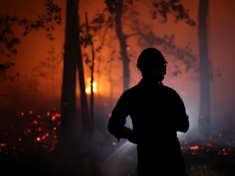 Een brandweerman probeert het vuur in het bos van Fontainebleau onder controle te krijgen.