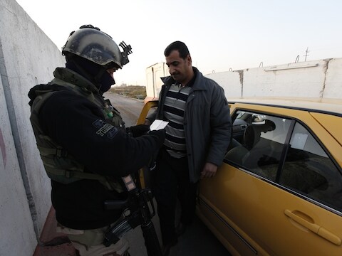 Een Iraakse soldaat controleert de identiteit van een automobilist nabij Bagdad. In het hele land zijn verscherpte controles in verband met de toegenomen gewelddadigheden.