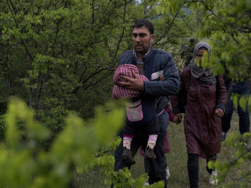 Syrische vluchtelingen steken illegaal de grens over tussen Macedonië en Griekenland.