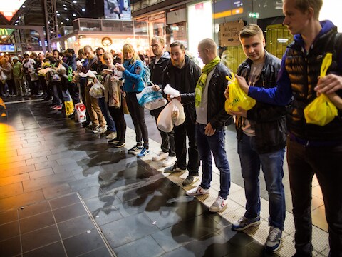 Vrijwilligers vormen een rij in het station van Frankfurt om vluchtelingen tassen met etenswaren te overhandigen.