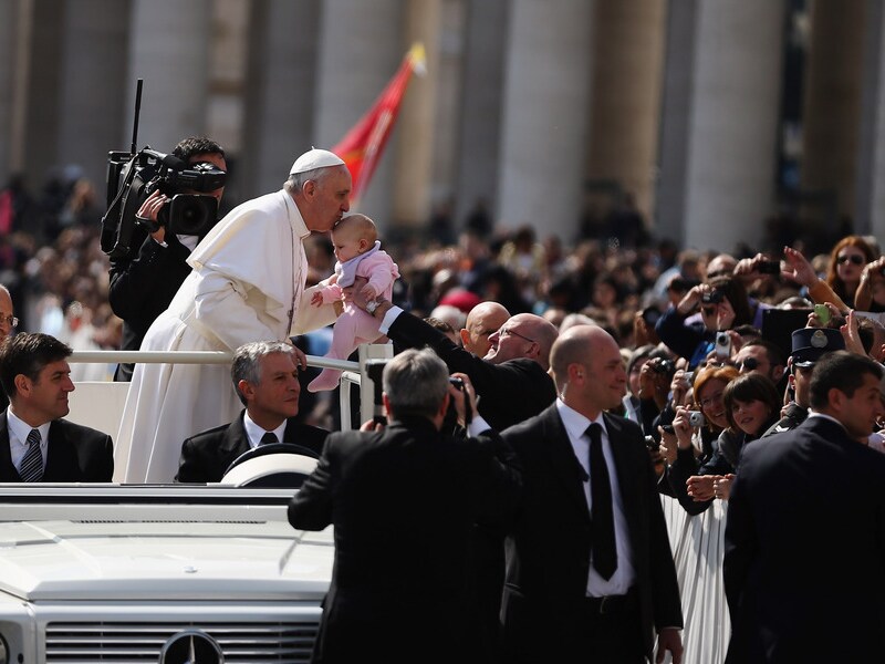 Paus Franciscus kust woensdag een baby tijdens een ritje over het Sint Pieterplein.