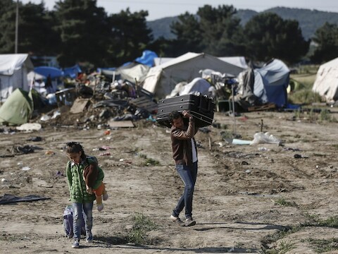 Syrische vluchtelingen tillen hun persoonlijke spullen uit het vluchtelingenkamp zodat ze overgeplaatst kunnen worden naar een nieuwe opvang.