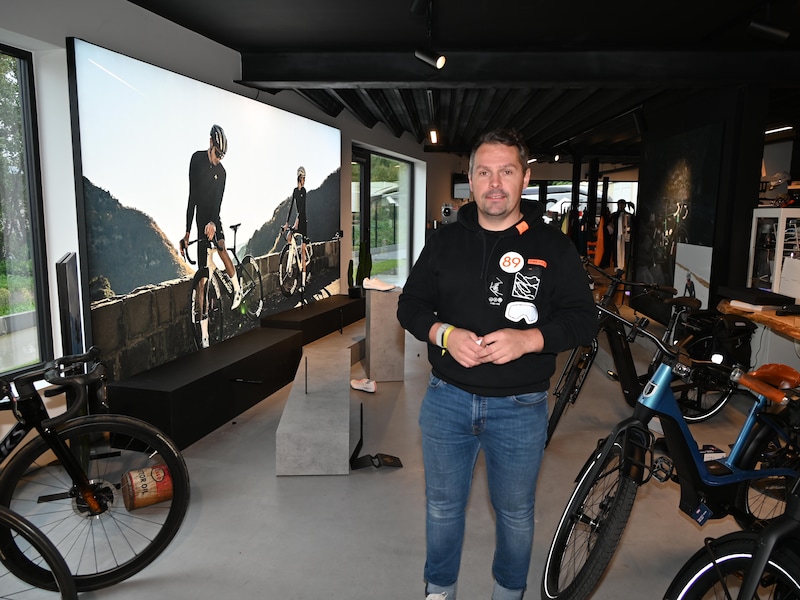 Zaakvoerder Tom Temmerman bij het winkelmeubilair waar de exclusieve racefietsen van Colnago aan verankerd waren.