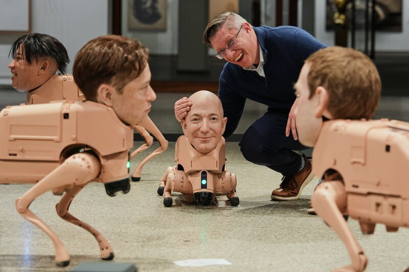 Artist Mike Winkelmann (Beeple), poses in his installation titled 'Regular Animals', with robots resembling Kim Jong Un (left), Elon Musk (second from left), Kim Jong Un, Jeff Bezos (center) and Mark Zuckerberg (right).