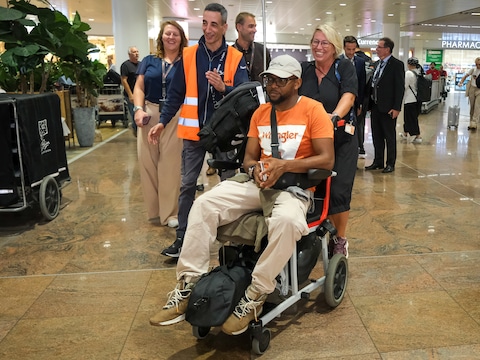Minister Gennez begeleidde een rolstoelgebruiker van de vertrekhal naar het vliegtuig.