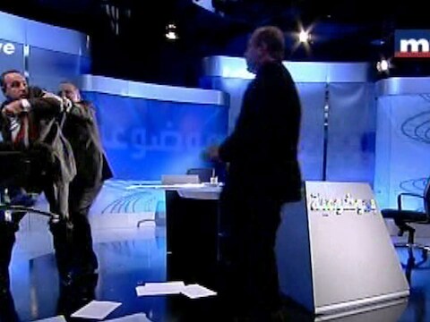 Shukr (links) wil een stoel gooien naar Alloush. De talkshowhost moet hem tegenhouden.