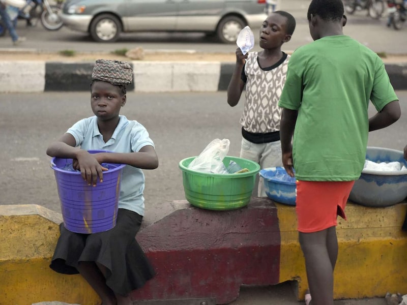 Nigeriaanse kinderen proberen hun waar te verkopen langs de kant van de weg