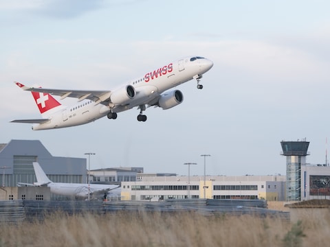 Een Bombardier CS300 van de luchtvaartmaatschappij Swiss International Air Lines stijgt op vanaf de internationale luchthaven van Dresden voor de verkeerstoren.