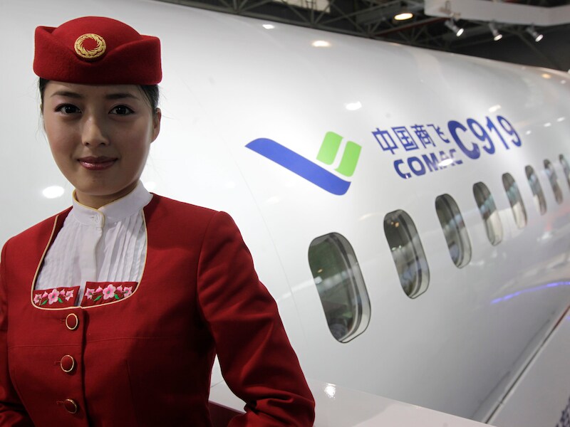 Een personeelslid van de Chinese luchtvaartmaatschappij Commercial Aircraft Corporation of China (Comac) poseert bij een voorbeeldmodel van een C919.