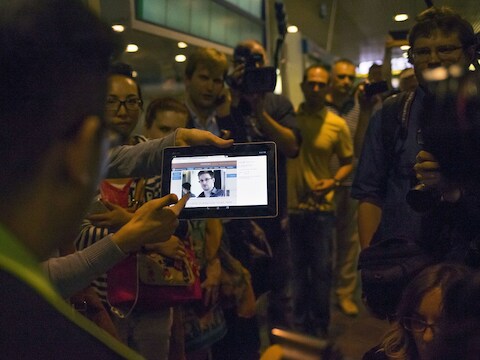 Een journalist houdt een tablet vast met daarop een foto van Edward Snowden op het vliegveld in Moskou.