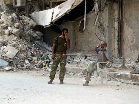Een militair van het Syrische leger in gesprek met een inwoner van een verwoeste straat in Aleppo.