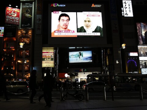 Een tv-scherm in Tokio toont een nieuwsprogramma waarin de foto's te zien zijn van de Japanse gegijzelde Goto en de Iraakse terreurverdachte tegen wie hij van IS moet worden uitgeruild.