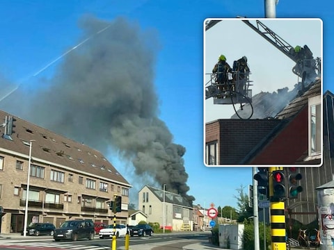 De rookpluim die uit het appartementsgebouw in Brecht opsteeg, was vanop grote afstand zichtbaar. Inzetfoto: de brandweer bij het vernielde dak.