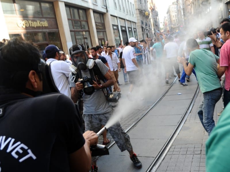 Een agent gebruikt traangas tegen betogers in Istanbul.