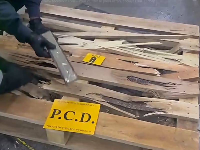 Een beeld uit de video waarop te zien is hoe de douaniers de drugs uit de pallets halen.