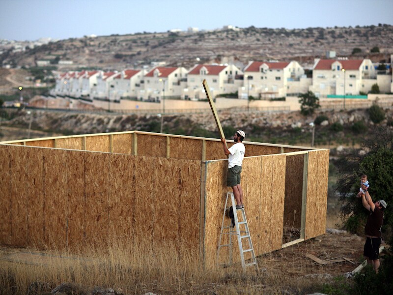 Een Israëlische kolonist bouwt een schuur nabij de nederzetting Kiryat Arba in Hebron, op de Westelijke Jordaanoever.