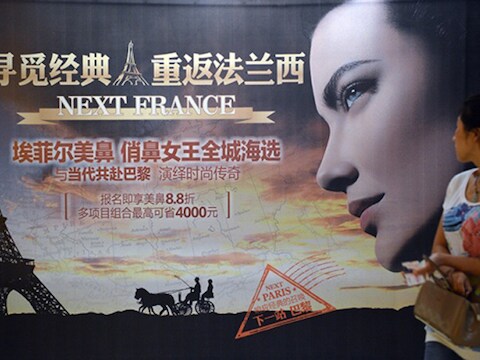 Een Chinese vrouw bekijkt een advertentie voor de zogenaamde 'Eiffeltorenneus'.