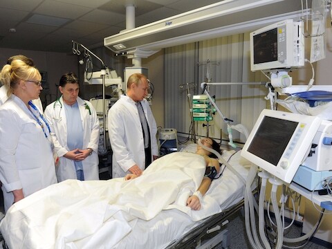 De Russische presindent Vladimir Putin bij het bed van Maria Komissarova.