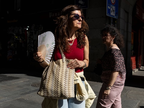 Een vrouw probeert af te koelen met een waaier in Madrid. 