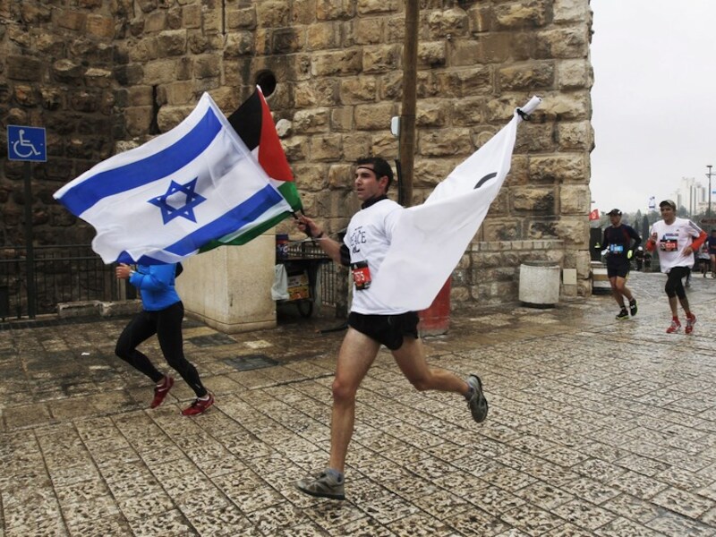 Een loper droeg vorige week een Israëlische, Palestijnse en witte vlag mee tijdens de marathon van Jeruzalem.