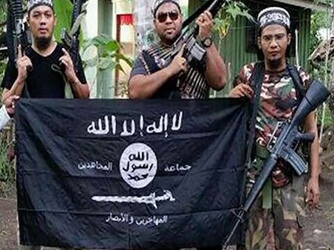 De Maleisische militanten Mahmud Ahmad, Muhammad Joraimee Awang Raimee en Muamar Gadafi poseren met IS-vlag.