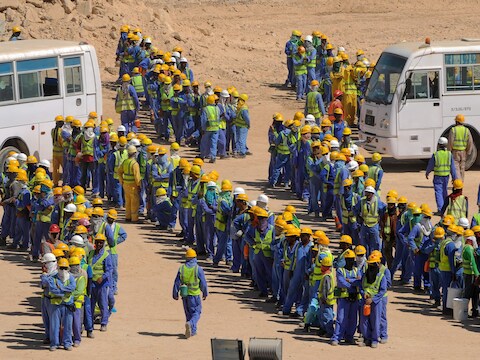 Arbeiders, die de WK-stadions bouwen in Qatar, verzamelen zich aan bussen.