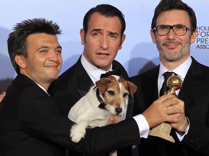 Producer Thomas Langmann (L), acteurJean Dujardin (C), regisseur Michel Hazanavicius én de hond Uggie poseren met hun Golden Globe.