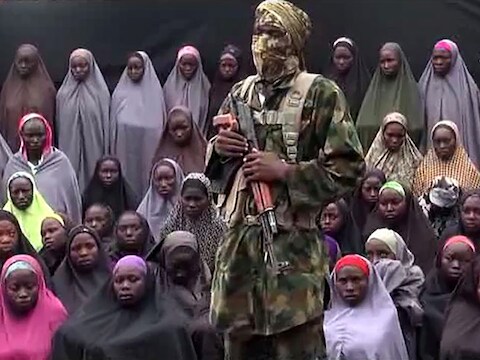 Archieffoto, waarop een Boko Haram-strijder voor een groep gekidnapte meisjes staat.