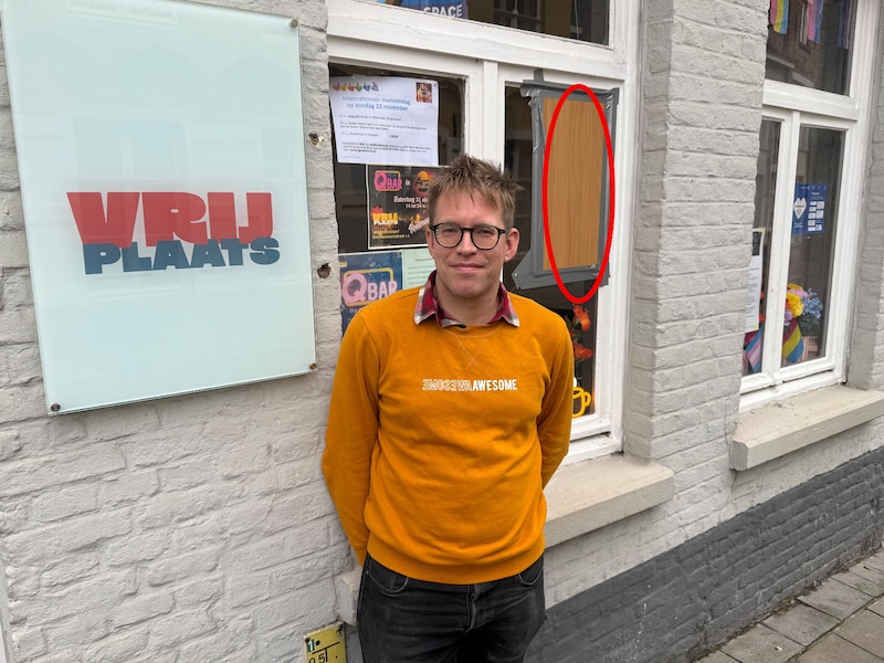 Pieter Vanroose aan het regenbooghuis in Brugge. Omcirkeld zie je de plek waar de steen door het venster ging.