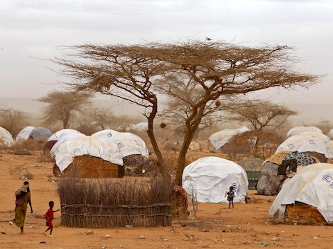 Vluchtelingen wandelen langs hutjes in het vluchtelingenkamp in Dadaab.