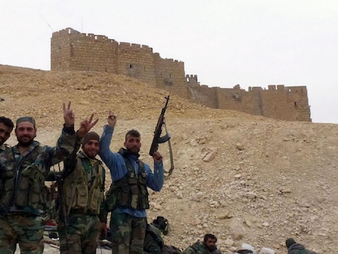 Syrische overheidstroepen vieren de herovering van Palmyra vlakbij de citadel van de stad.