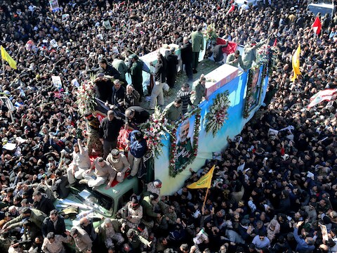 Een voertuig met daarin de kist van Qassem Soleimani baant zich een weg door de massa in de Iraanse stad Kerman.