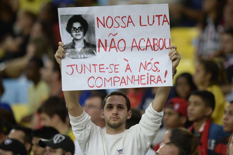 Een betoger houdt een poster in de lucht met de foto van president Dilma Rousseff met als tekst "De strijd is niet over. Vervoeg ons, vriendin".