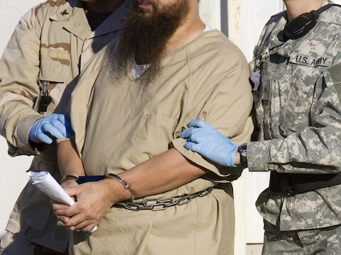 Een gevangene op Guantánamo Bay wordt weggeleid.