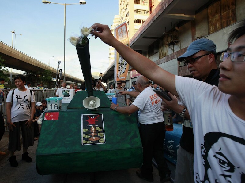 Demonstranten in Hong Kong steken bloemen in een nagebouwde tank tijdens de herdenking van het bloedbad op het Tiananmenplein