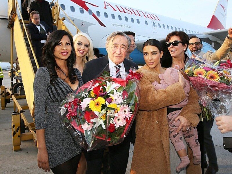 Kim Kardashian (tweede van rechts) en haar moeder Kris Jenner (rechts) worden door de Oostenrijkse miljardair Richard Lugner (midden) op het vliegveld in Wenen verwelkomd.