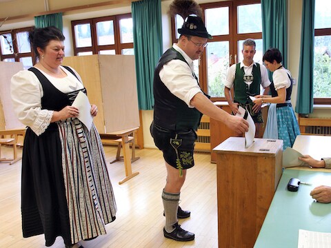 Duitse stemgerechtigden gaan stemmen in traditionele outfit.