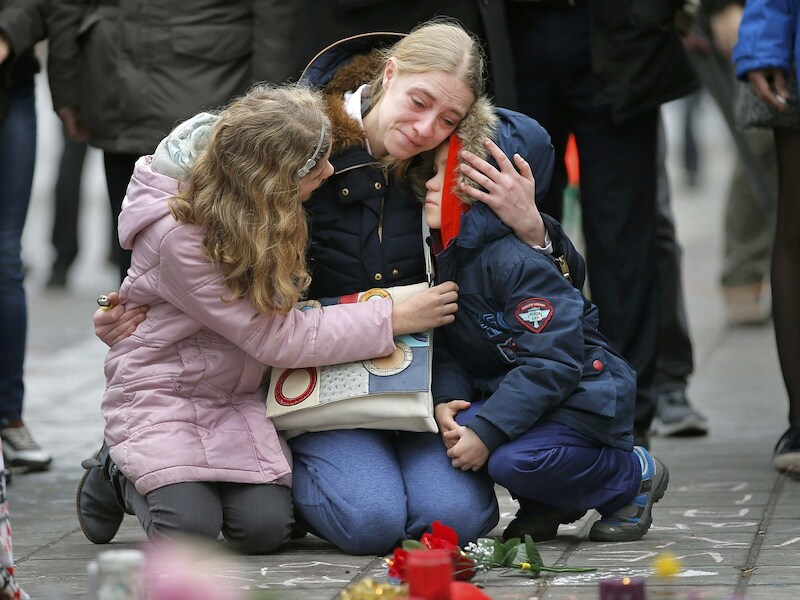 Een vrouw en haar kinderen leggen bloemen neer in Brussel.