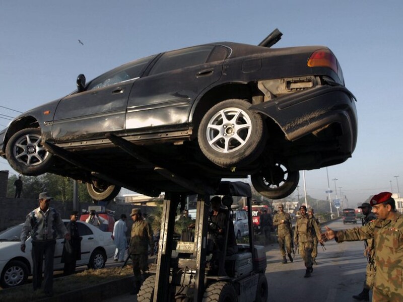 Een auto die beschadigd raakte bij een bomaanslag op het regionaal hoofdkwartier van de Pakistaanse geheime dienst ISI wordt weggetakeld in Peshawar.
