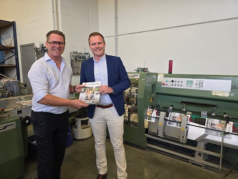 Burgemeester Mathias Van de Walle krijgt het eerste exemplaar uit handen van drukker Lieven De Maertelaere.