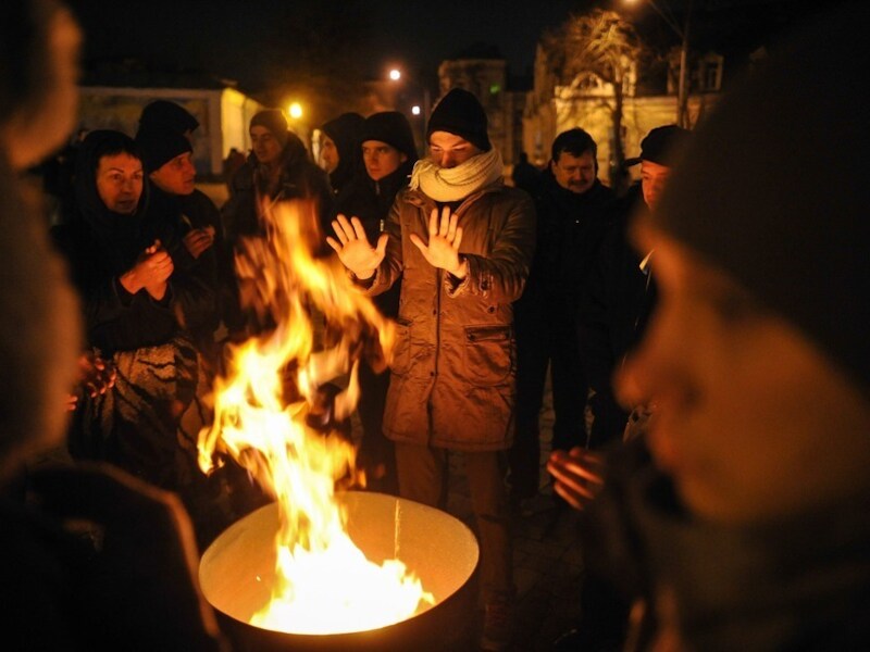 Manifestanten warmen zich op het Mikhaylivskaplein in Kiev.