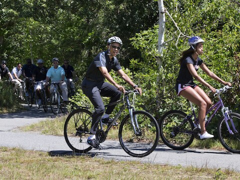 Barack Obama maakt tijdens zijn vakantie een fietstochtje met zijn dochter Malia, waarbij hij gevold wordt door beveiligers