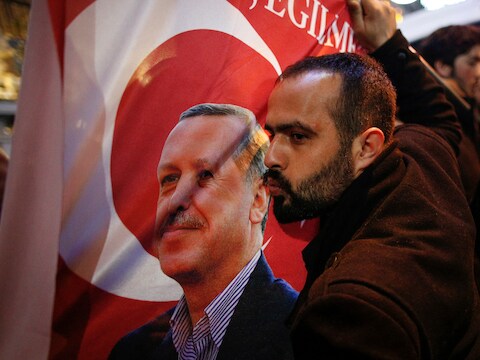 Een betoger kust een vlag met de beeltenis van Turks president Erdogan, gisteren voor het Nederlands consulaat in Istanboel.