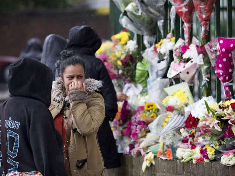 Een vrouw kijkt naar de bloemen die achtergelaten zijn op de plek waar Lee Rigby werd vermoord.