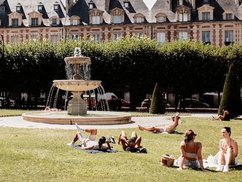 Zonnekloppers op de Place des Vosges in Parijs tijdens een hittegolf. 