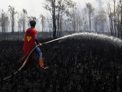 Rudiyansah (17) helpt in een Supermankostuum vrijwillig bosbranden blussen in het Indonesische Palangkaraya.
