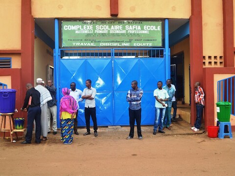 Mensen staan te wachten aan een school in de hoofdstad Conakry op de eerste schooldag in vijf maanden.