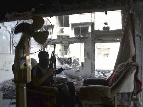 Een lid van het Vrije Syrische leger zit in een kapotgeschoten huis